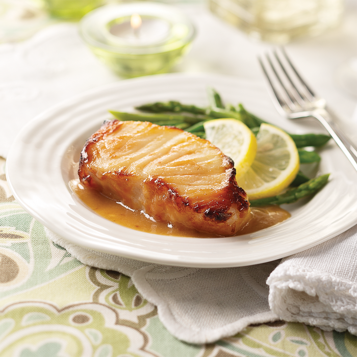 one miso sea bass filet on a plate with lemon and green beans.