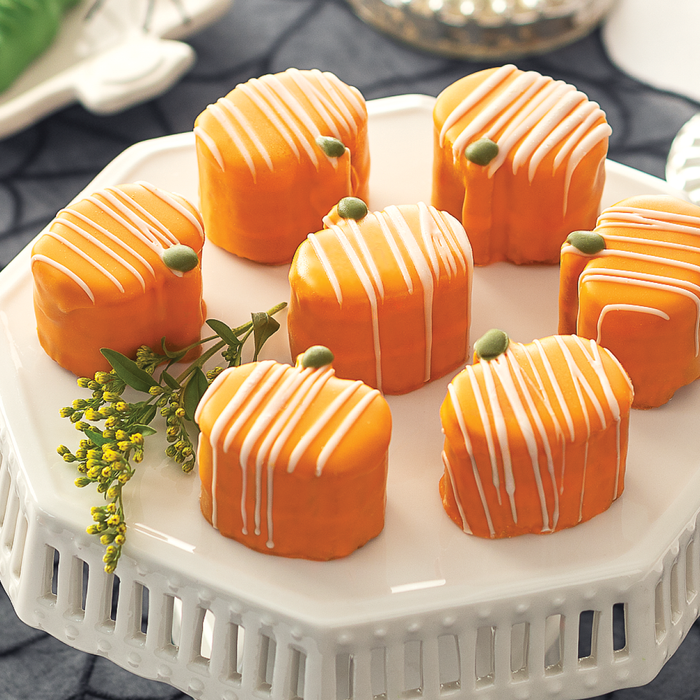 Orange Pumpkin Tea Cakes with white lined frosting on a tray