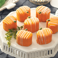 Orange Pumpkin Tea Cakes with white lined frosting on a tray