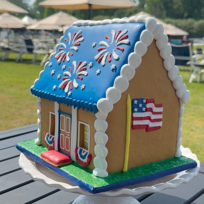 Star-Spangled Cookie House at side angle with American Flag in an outdoor setting